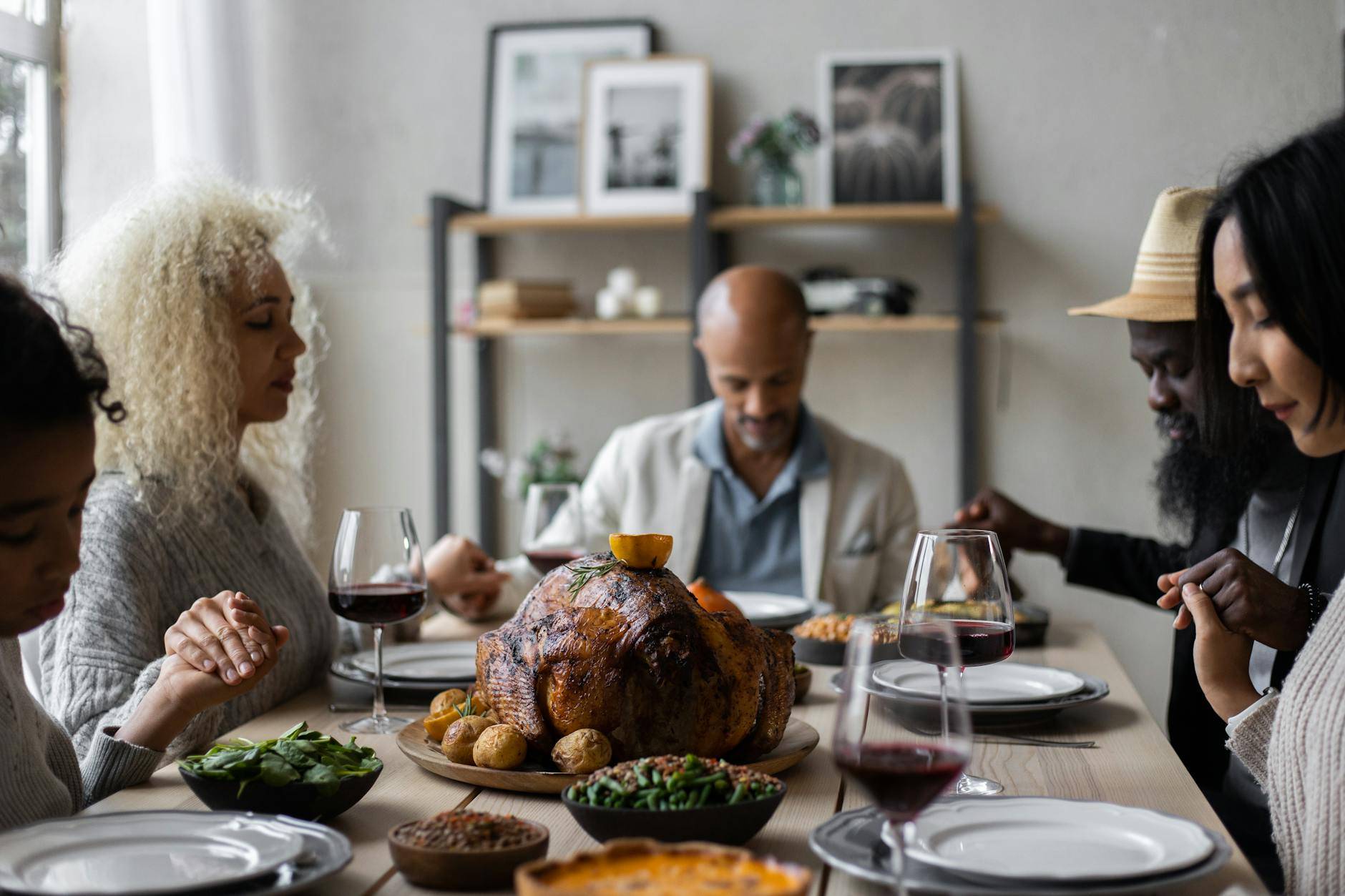 diverse people holding hands and praying at table